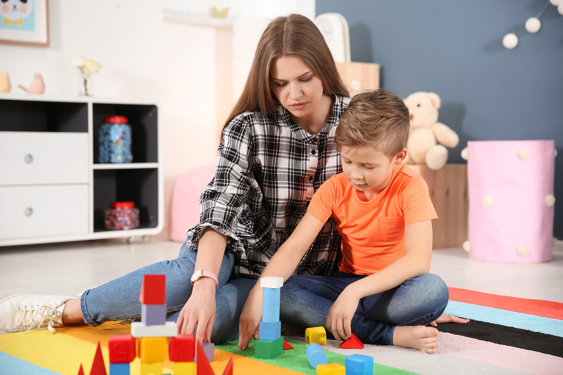 ABA Therapist with little boy with ASD working with building blocks